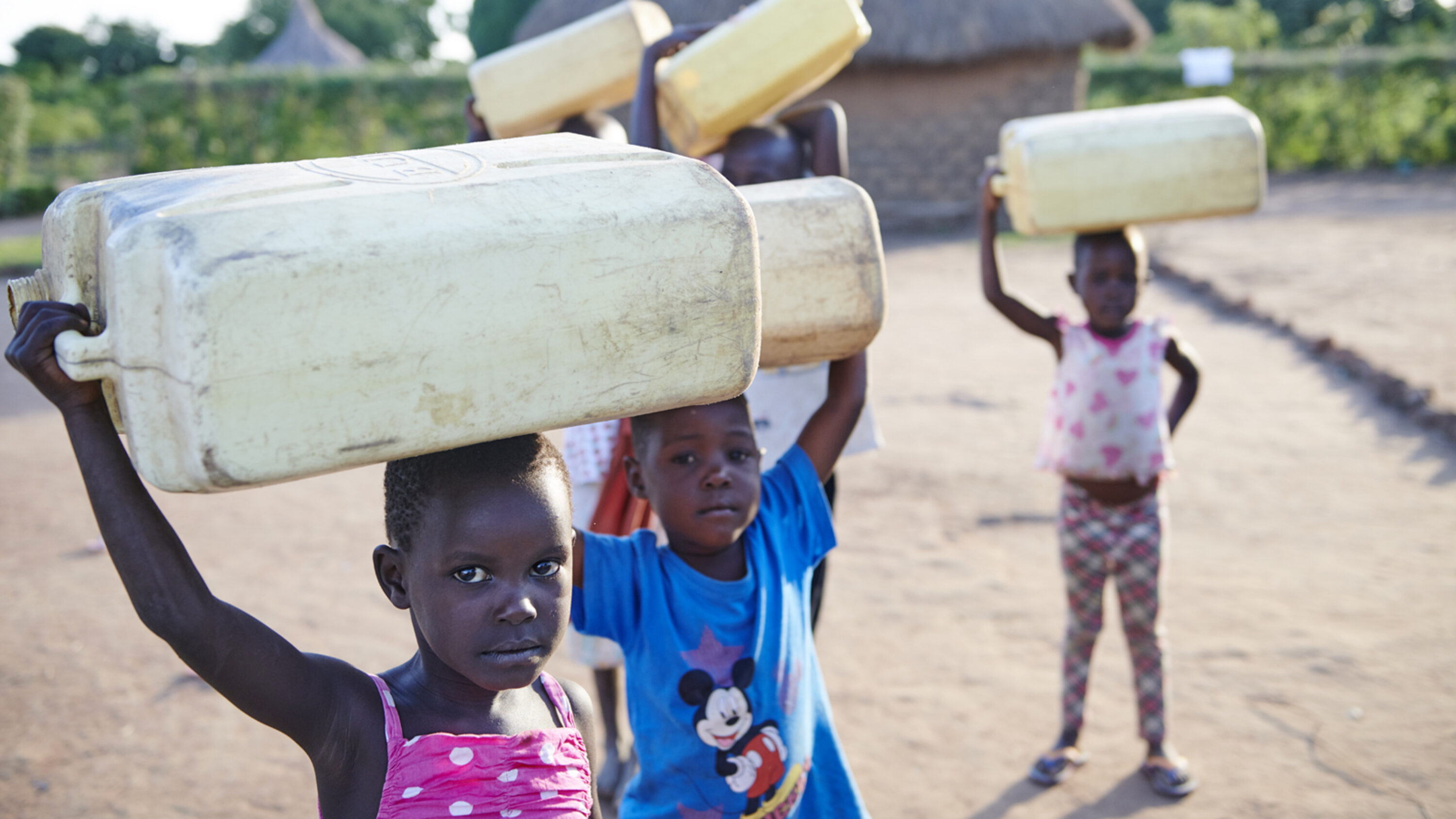 Kinder in Afrika tragen Wasserkanister