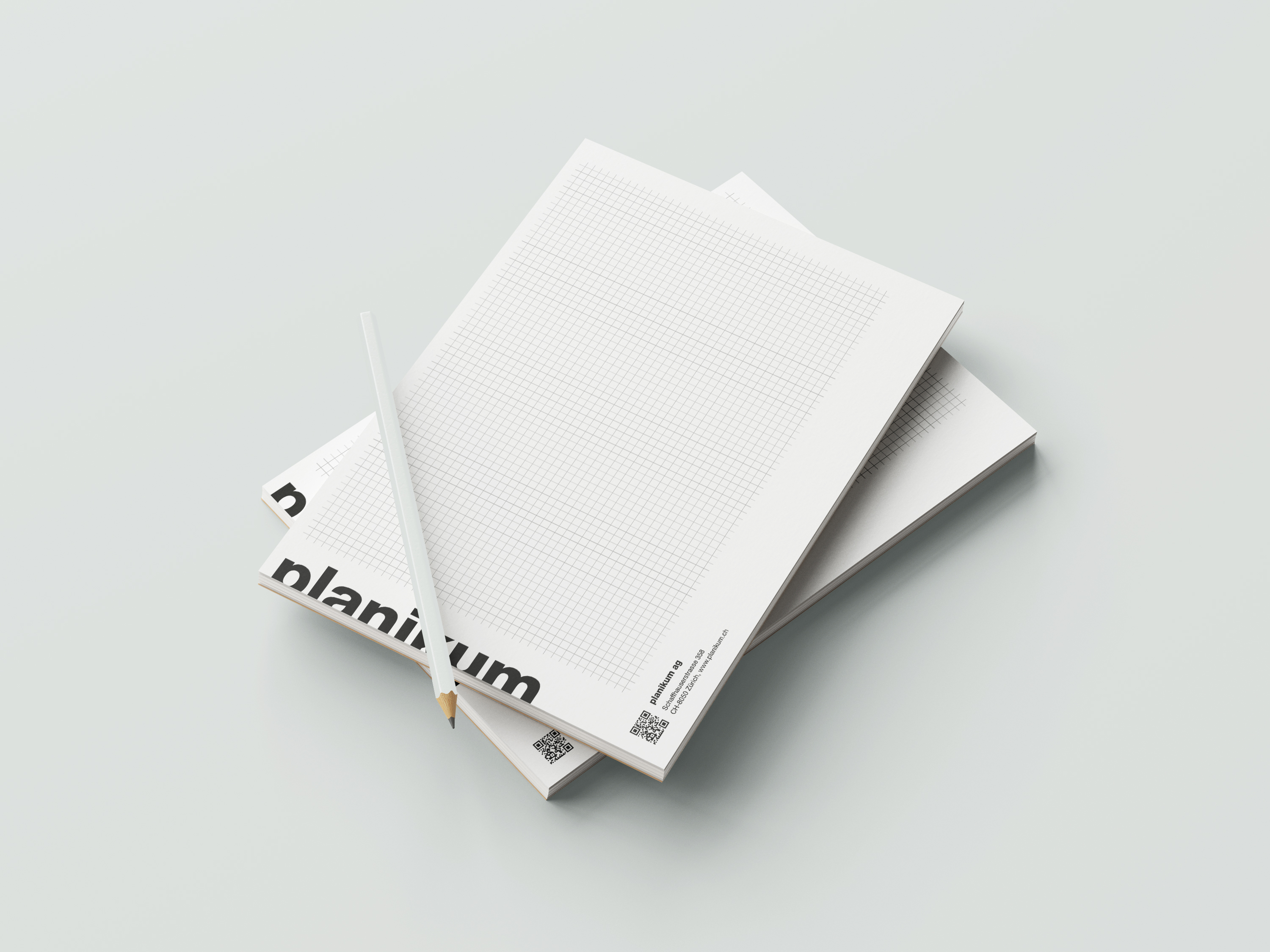 Notizblöcke mit Planikum Logo und Bleistift auf hellem Hintergrund